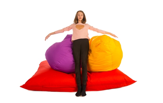 Girl standing near beanbag chairs and beanbag sofa isolated on white