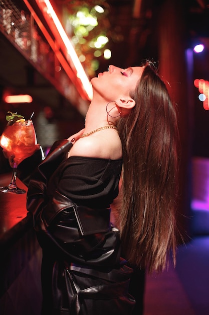 Girl standing in a night club with colorful bright neon red lights