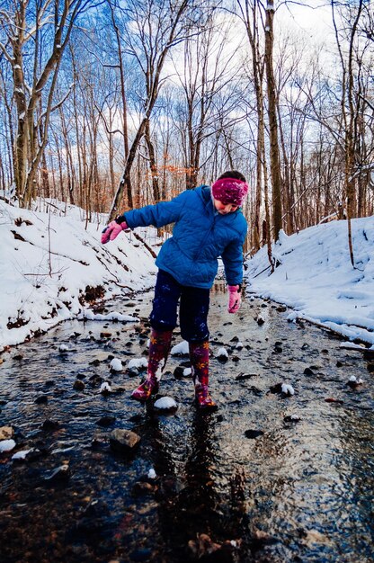 Photo girl standing in stream at forest during winter