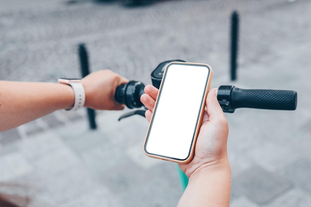 Girl standing with electric scooter and showing the phone with blank white screen