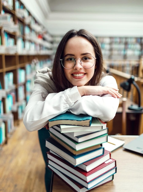 Девушка стоит со сложенными руками на книгах в библиотеке