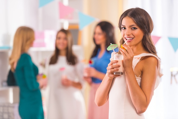 Girl stands drinking a cocktail and smiling at front