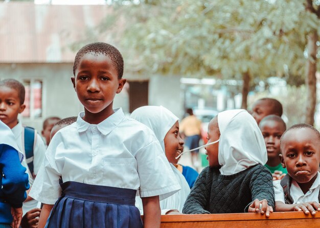 A girl stands in front of a school bench.