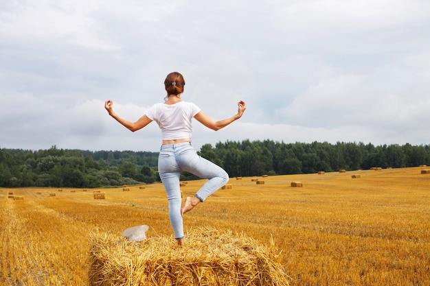 Girl stands on a haystack on a bale