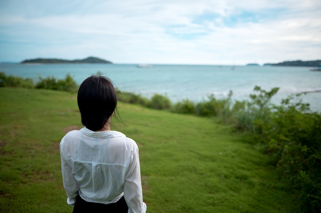 女の子は彼女の背中と丘の上に立って、海を見て