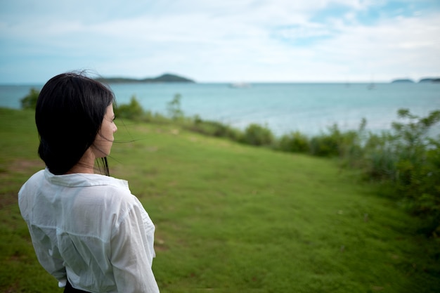 女の子は彼女の背中と丘の上に立って、海を見て