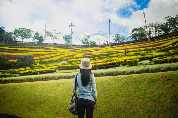 The girl stands looking at the beauty of the ornamental garden.