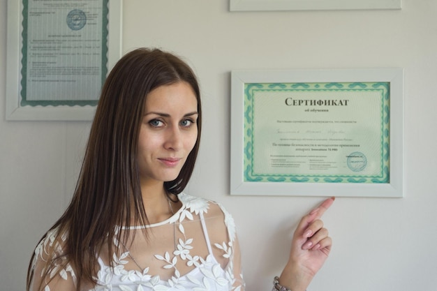 A girl stands near the wall with the certificates of quality 9112