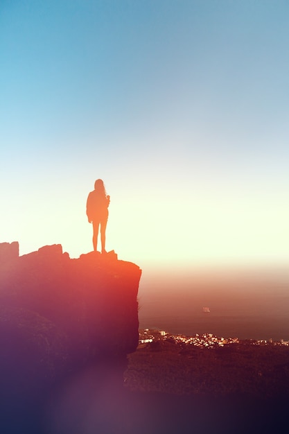 A girl stands on a rock high in the Ai-Petri mountains in the Crimea at sunset. The sea in the background Vacation travel