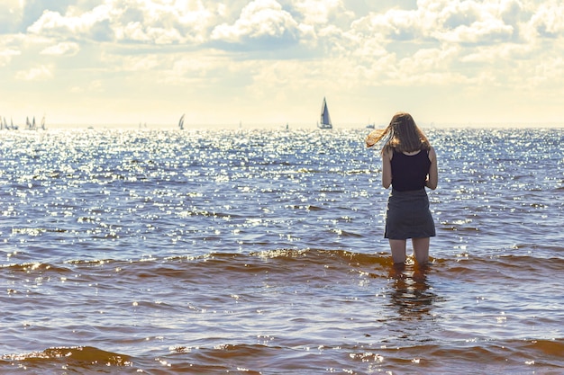 A girl stands in sea water while on vacation.