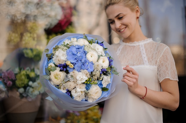 Girl stands with bouquet with white and blue flowers