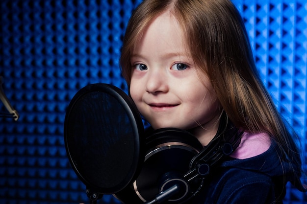 Girl star singer artist in a black blouse with headphone\
recording new song with microphone