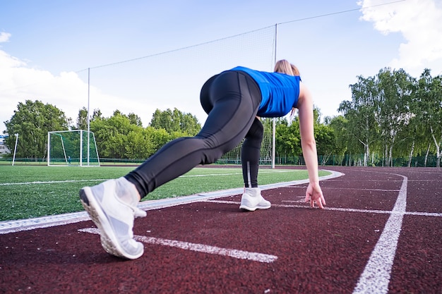 Girl at start of running track. Running on cross. Sports start. girl in pose on the starting line of treadmill. Active lifestyle. Concept of moving forward