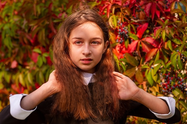 A girl straightens her curly hair in nature. Schoolgirl portrait.