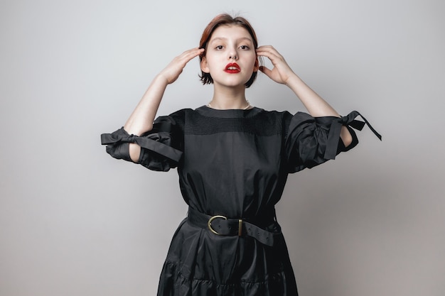 A girl straightens her hair against a white wall