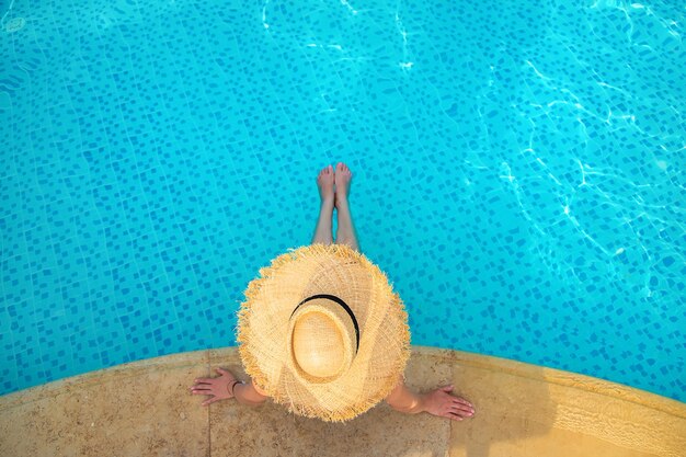 Girl in a straw hat inside the swimming pool, aerial view