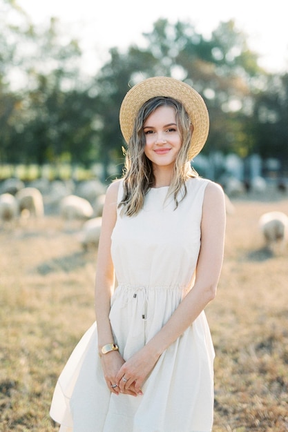 Girl in a straw hat stands on the lawn