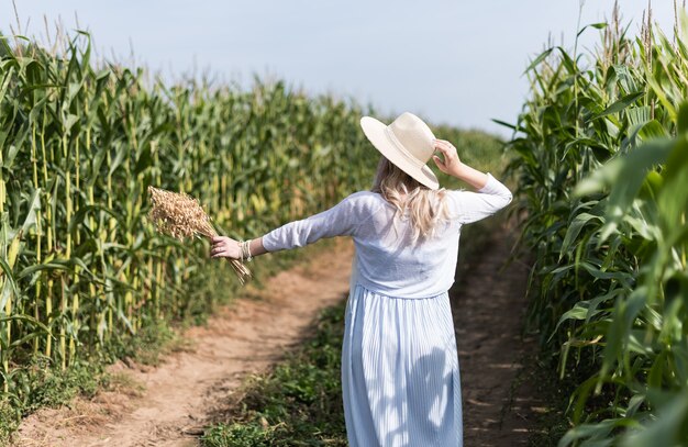 A girl in a straw hat walks in the corn field