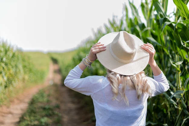 A girl in a straw hat walks in the corn field
