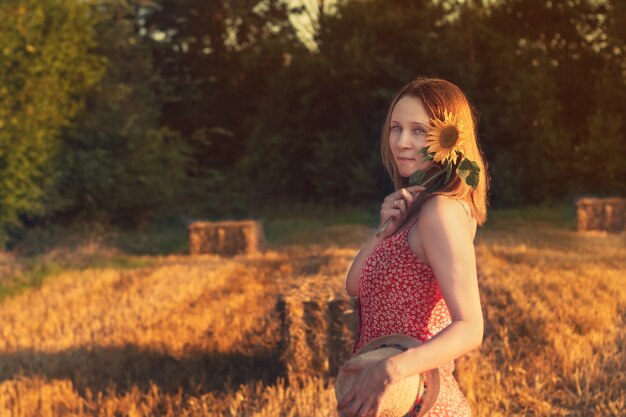 Ragazza con un cappello di paglia con un fiore sul fieno