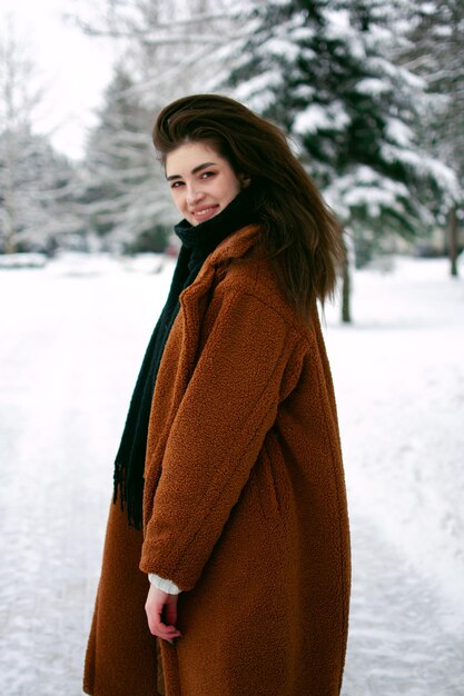 La ragazza per strada in inverno sta nevicando sulle mani della ragazza con i guanti. inverno 2022.