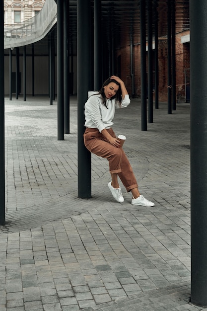 Girl on the street with a disposable paper cup. Take away food, walk around the city.