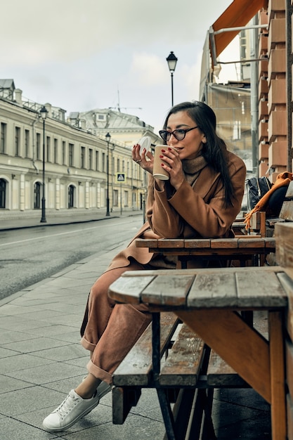 Girl on the street with a disposable paper cup. Take away food, walk around the city.