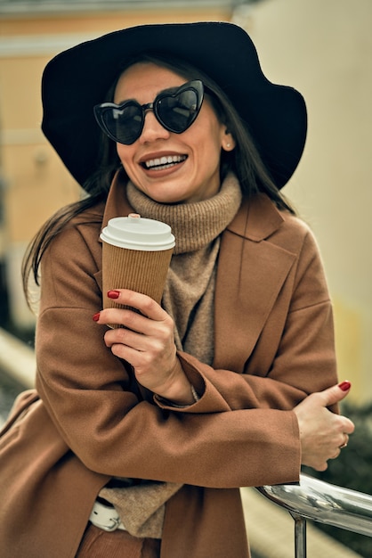 Girl on the street with a disposable paper cup. Take away food, walk around the city.