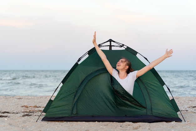女の子は朝テントでストレッチします。海でのキャンプ。旅行、ハイキング、キャンプ。