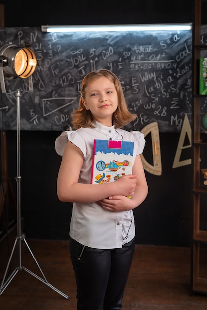 Photo a girl in strict clothes stands at a school blackboard with inscriptions