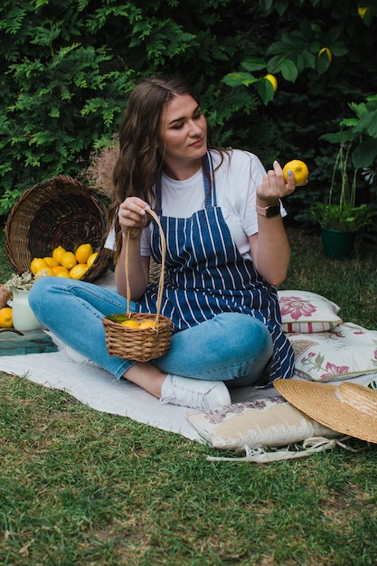 A girl in a striped apron and a straw hat sits on the grass near the house