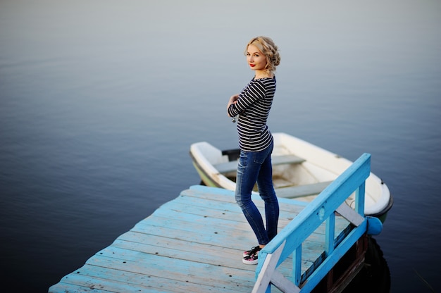 Girl in a striped blouse standing on a wooden bridge on a background of the river