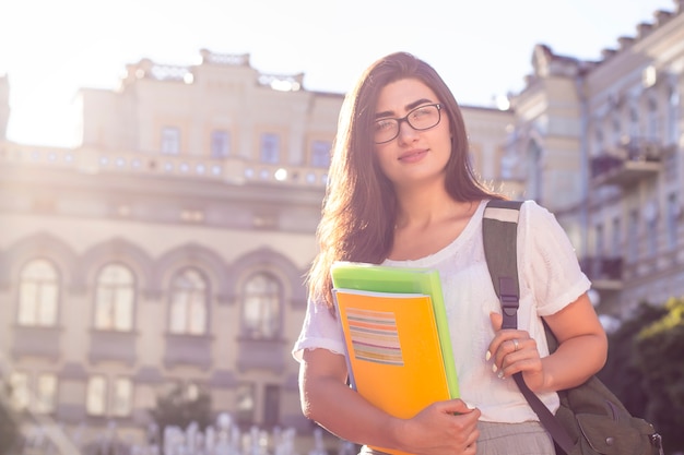 Girl student in glasses on the background of the university. 