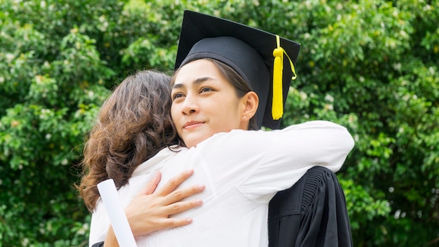 Girl student with the Graduation gowns and hat hug the parent in congratulation ceremony.
