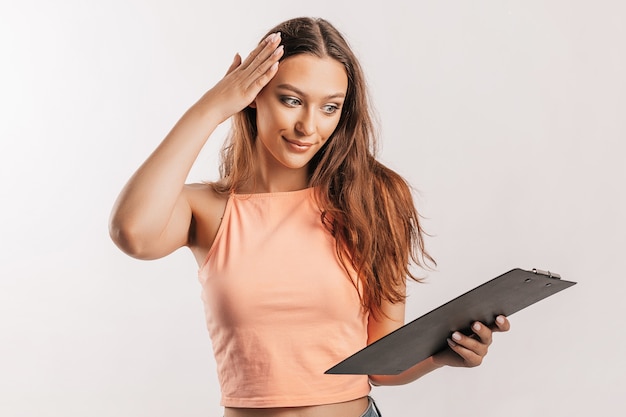 Girl student writes information. Beautiful young business woman isolated on gray background. Achieving career wealth business concept. Mockup copy space. Hold a clipboard with documents