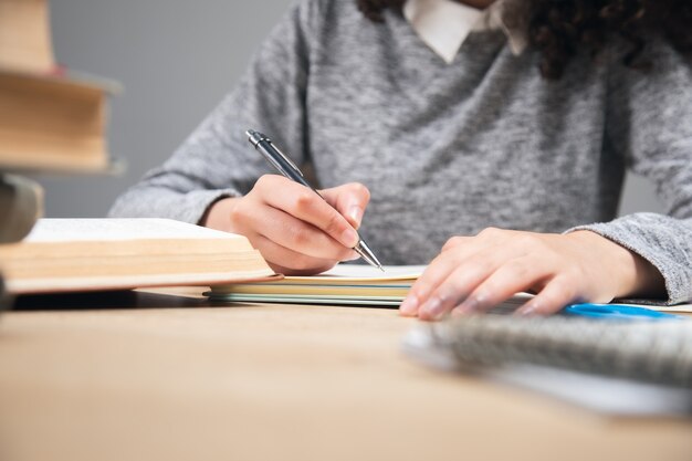 Girl student writing in notebook with stack books