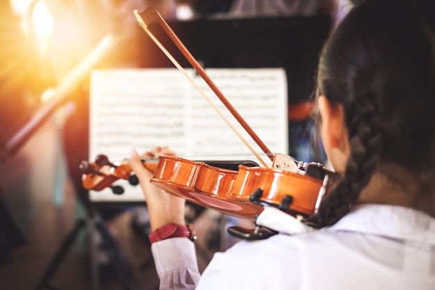 girl students playing violin in the group.