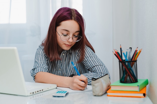 Girl studying at home working with laptop and doing homework