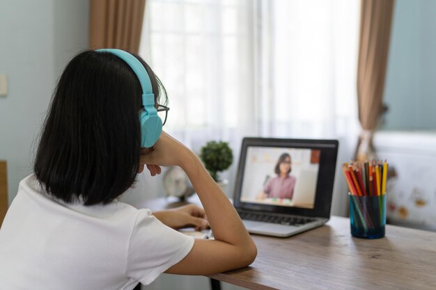 写真 家でラップトップでオンラインで勉強している女の子