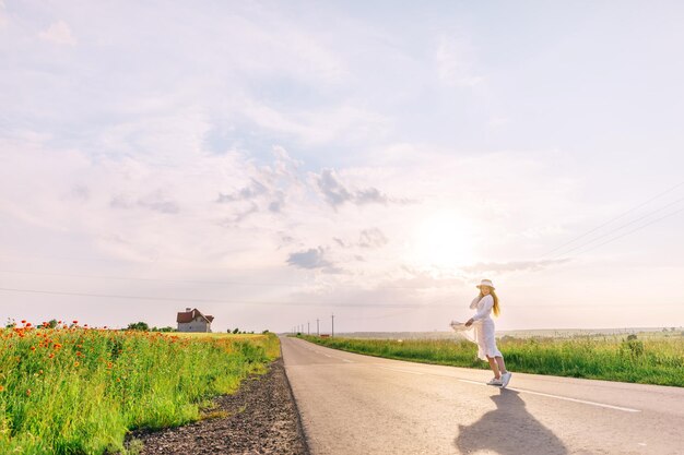 道路の青い空と赤いポップでポーズをとるスタイリッシュな服の女の子