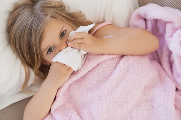 Girl suffering from cold as she lies in bed