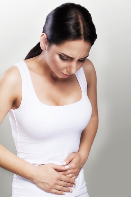 A girl suffering from a painful stomach holding hands on her stomach