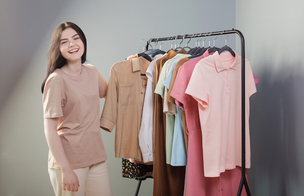 Girl next to summer clothes on  hanger at home