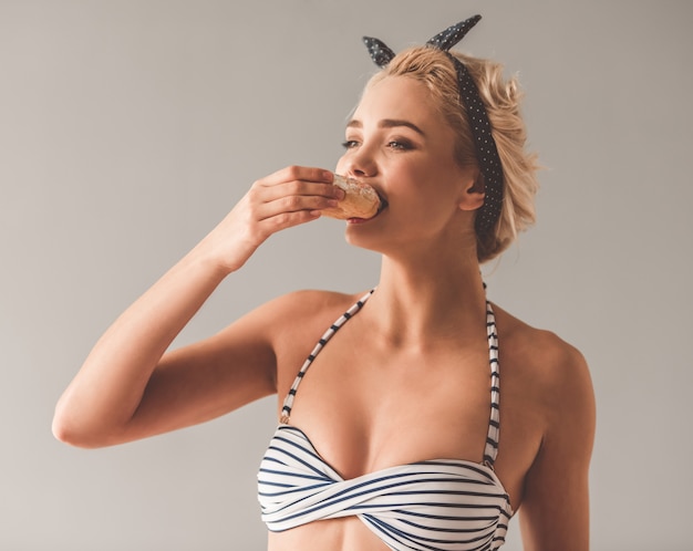 Girl in summer clothes is eating doughnuts and smiling