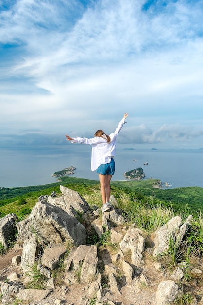 Girl in summer clothes on the top of the mountain near the sea