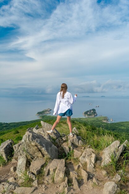 Girl in summer clothes on the top of the mountain near the sea