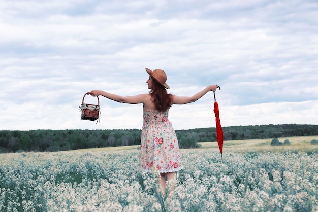 Girl in a summer meadow with white flower in cloudy day