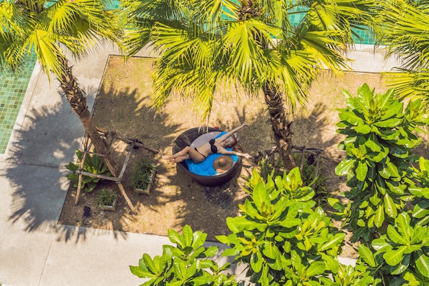 Girl in sun loungers among palm trees near the swimming pool.