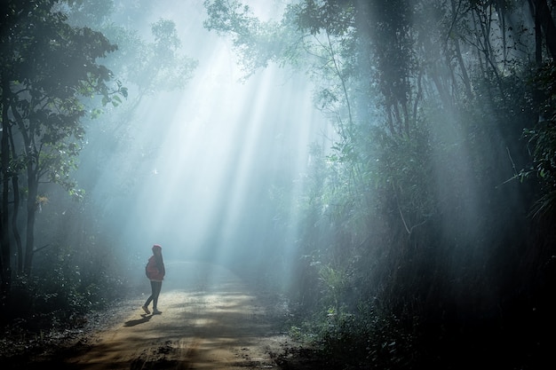 Girl in sun rays coming through the trees in forest