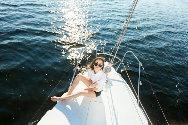 Девушка в солнцезащитных очках отдыхает на парусной яхте